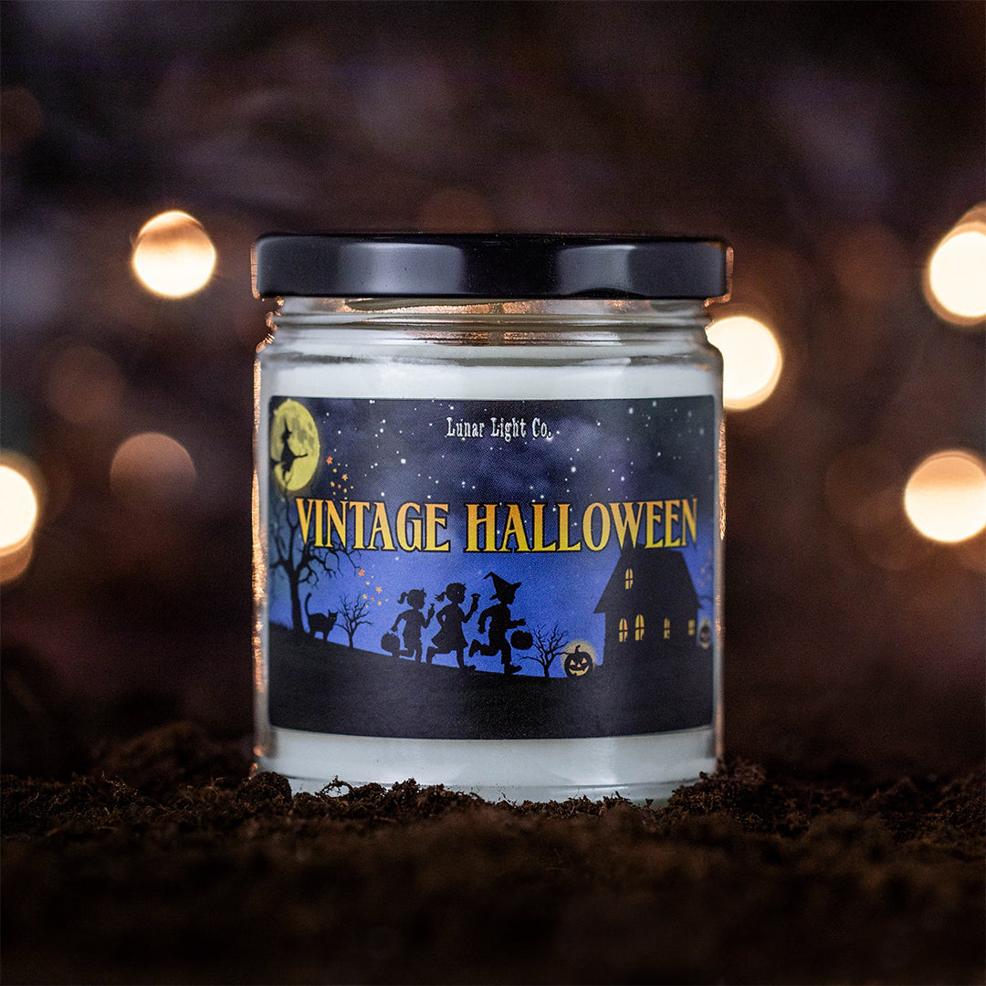 Vintage Halloween candle displayed on dirt with mysterious lights in background