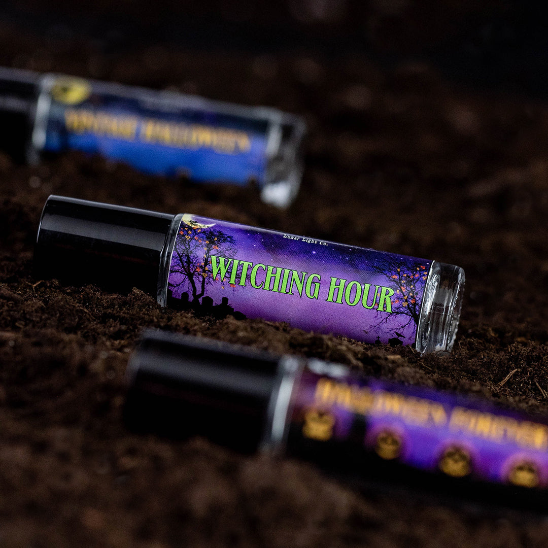 Perfume Oil roll on bottles displayed on dirt. One in focus, 2 out of focus