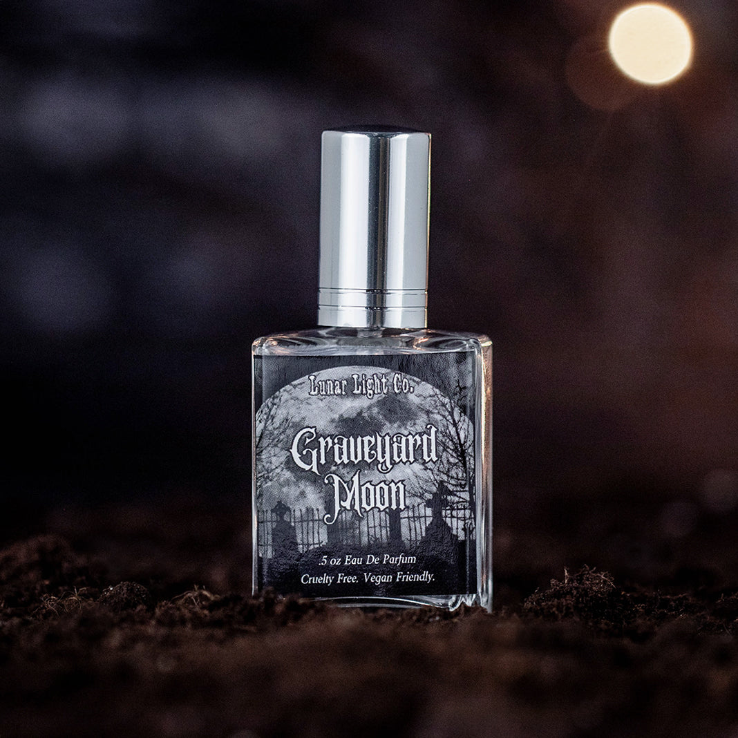 Graveyard Moon eau de parfum bottle displayed on dirt with a foggy, moonlit atmosphere