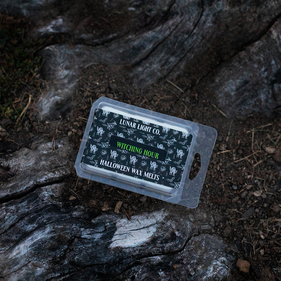 Halloween wax melt package sitting on a dirt covered tree stump