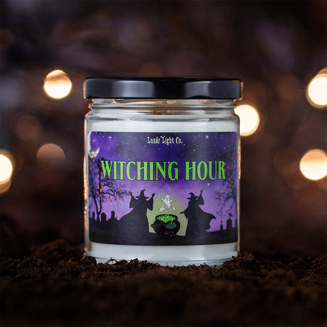 Witching Hour candle on dirt with bokeh lights in the foggy, mysterious background