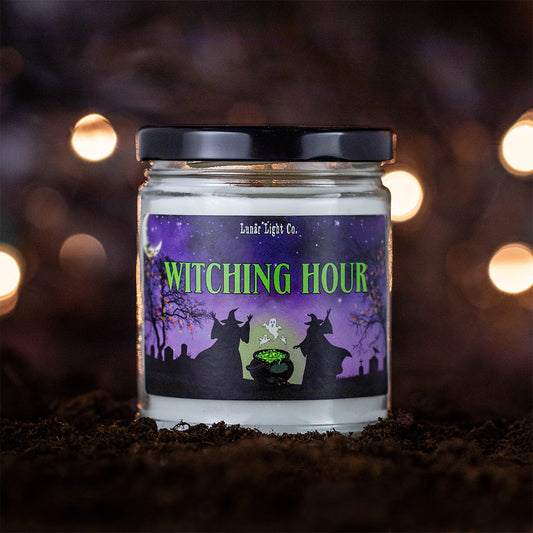 Witching Hour candle on dirt with bokeh lights in the foggy, mysterious background