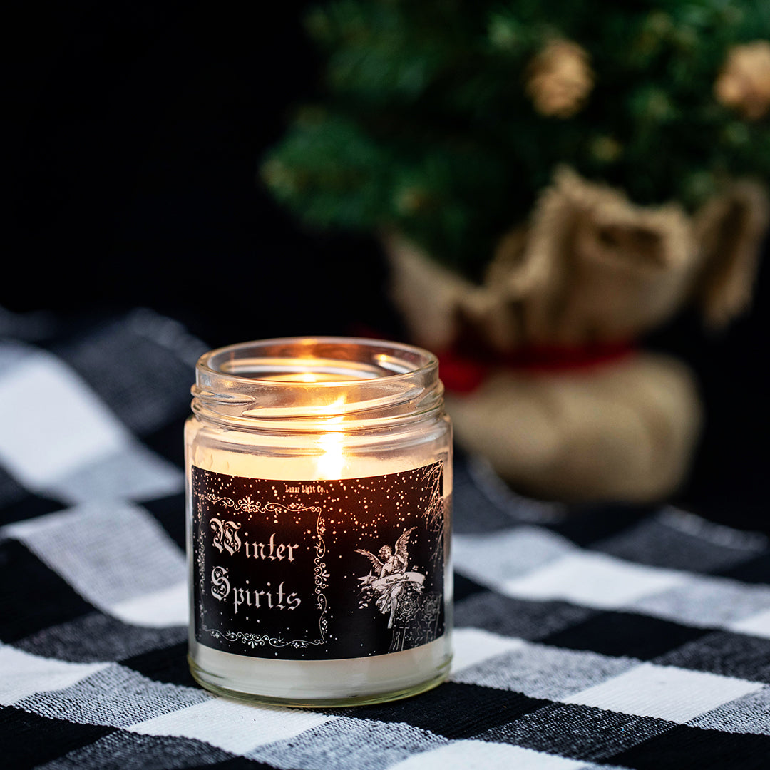 lit winter spirits candle with christmas tree in background